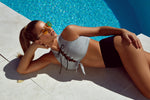 Woman in a gray bikini lying by a pool