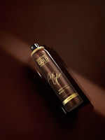 Dropping Gold hair spray bottle on a dark brown background