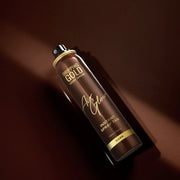 Dropping Gold hair spray bottle on a dark brown background