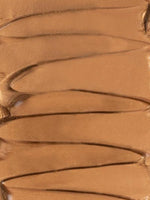 Close-up of the dropper releasing the shimmery bronze elixir
