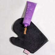 Purple hair color product with a black applicator glove on a white background