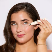 Woman applying concealer to her face with a makeup brush.