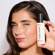Woman holding a Skinstudio product against a plain background