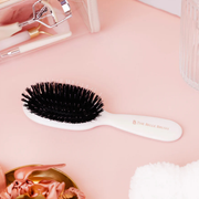 Flatlay of The Smoothing Brush with hair styling accessories