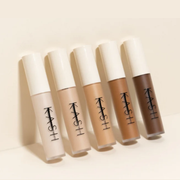 Five KASH concealer bottles in various shades on a beige background
