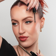 Woman applying mascara with a close-up of her eye and hand.