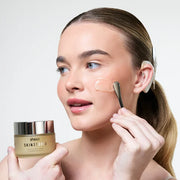 Model gently applying BPERFECT cleansing balm to her cheek