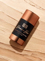 Bronzer stick with 'Dripping Gold' branding on a beige background